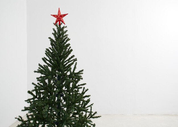 Foto Árbol de navidad mínimo con estrellas decorativas rojas el espacio de copia de la habitación blanca