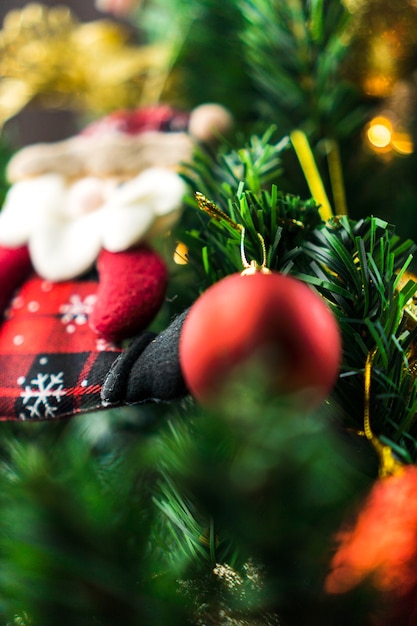 Foto Árbol de navidad montado con adornos. bolas rojas, plateadas y doradas, cajas regalo, luces, papá noel y otros. enfoque selectivo.