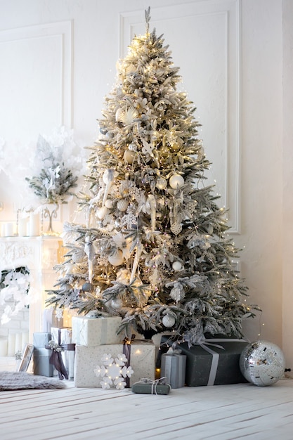 árbol de Navidad plateado claro y esponjoso, regalos en cajas grises y otras decoraciones en una habitación luminosa