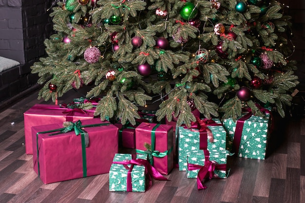 Foto un árbol de navidad con regalos rosas y verdes debajo.