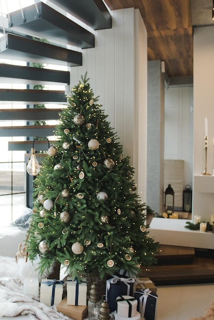 Árbol de Navidad en la sala de estar. Año nuevo. Árbol de Navidad con adornos y luces de hadas. Fondo de Navidad. Árbol de Navidad en color blanco y dorado.