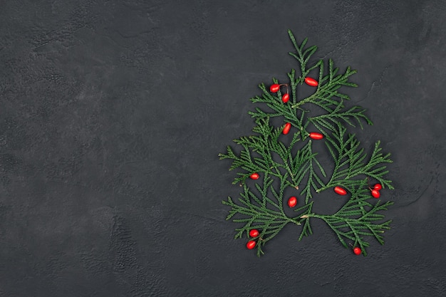 Foto Árbol navideño de ramitas verdes y frutos rojos sobre un negro