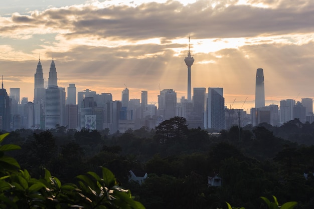 Foto Árboles y edificios contra el cielo nublado durante la puesta de sol