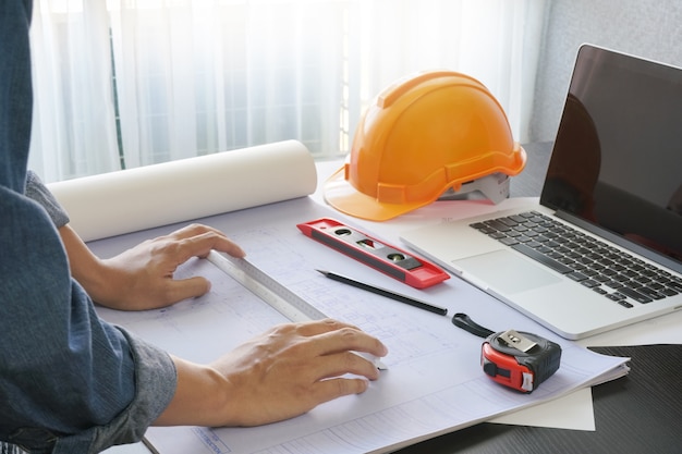 Architekt, der an Tabelle mit Plan- und Bauwerkzeugen arbeitet
