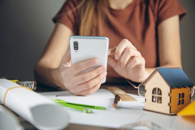 Architekt hält Telefon vor Schreibtisch