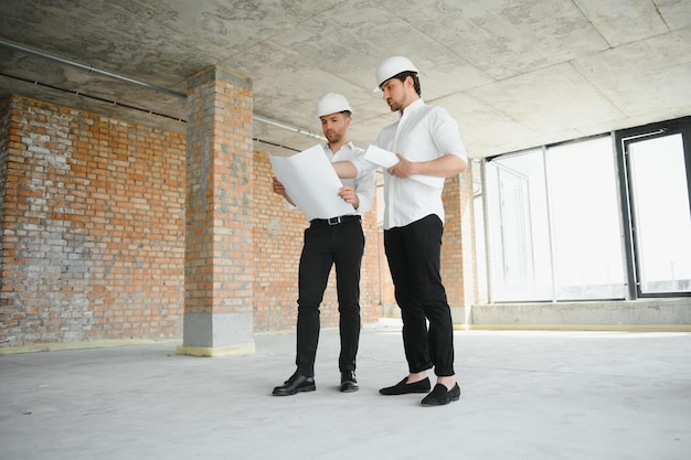 Architekt mit zwei jungen Männern auf einer Hochbausite