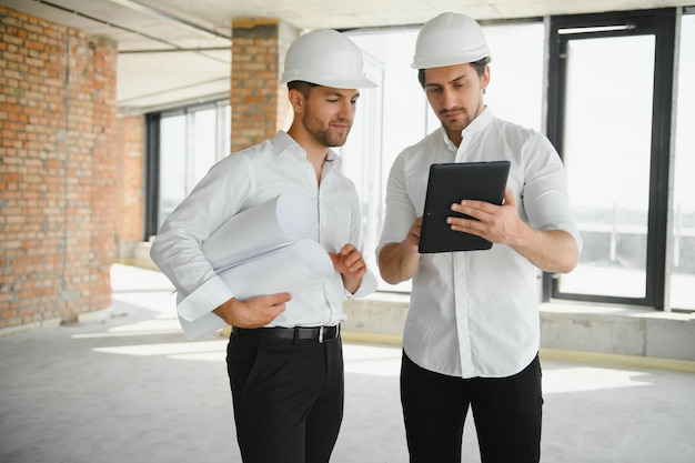 Architekt mit zwei jungen Männern auf einer Hochbausite