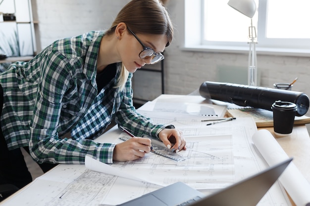 Architekt zeichnet Blaupausen im Büroingenieur, der einen Architekturplan für ein Bauprojekt skizziert ...