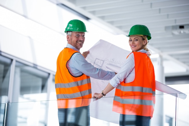 Architekten diskutieren mit Blaupause im Bürokorridor