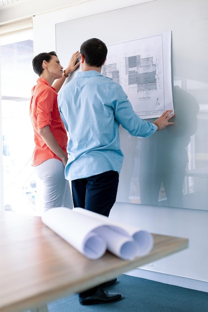 Architekten diskutieren über eine Blaupause auf einer Glasplatte in einem modernen Büro