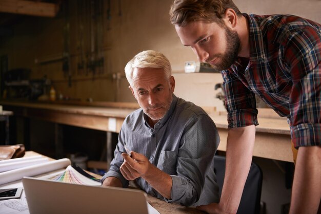 Foto architekten-teamarbeit und vater und sohn mit laptop in der werkstatt für den hochbau. leitende ingenieure und computer mit praktikanten oder lehrlingen, die mit mentor an entwurf und planung arbeiten