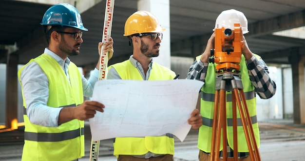 Architektenteam in der Gruppe auf der Baustelle prüft Dokumente