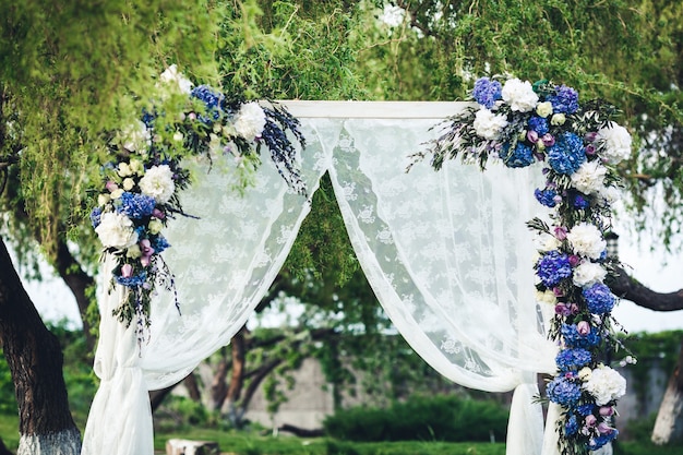 Arco de boda decorado con tela y flores.