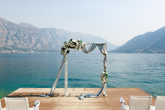 Arco de boda se encuentra en un muelle de madera con vistas a las montañas