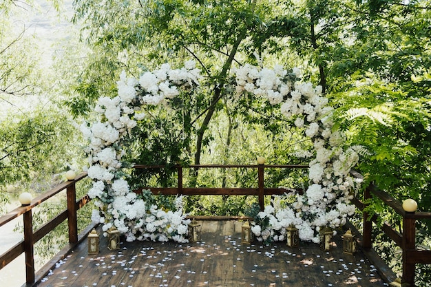 Arco de boda redondo decorado con flores blancas y vegetación.