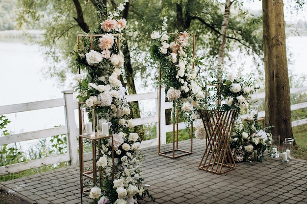 Arco de bodas con flores frescas de rosas junto al lago en el parque