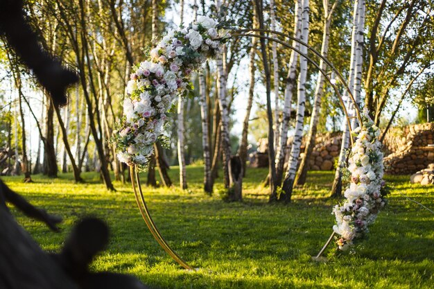 Arco de bodas con guirnaldas de flores frescas en el césped en el parque