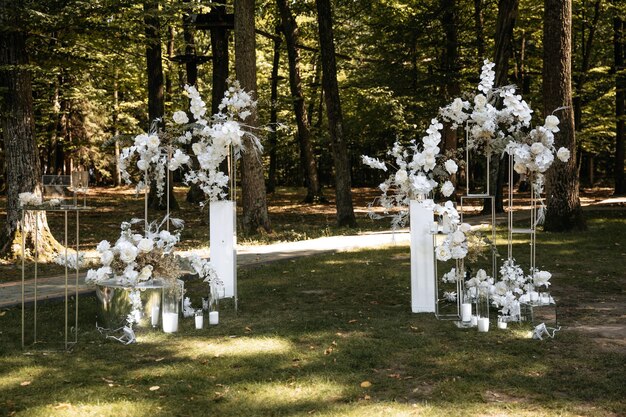 Foto arco de bodas de lujo hecho de flores blancas exuberantes en el fondo de un bosque verde en verano