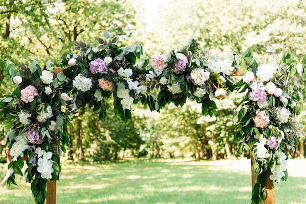 Arco para la ceremonia de la boda. Arco, decorado con hermosas flores frescas y tela. Inscripción en el lugar de matrimonio.