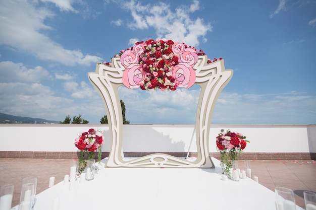 Foto arco com flores frescas vermelhas em um fundo de mar e céu azul