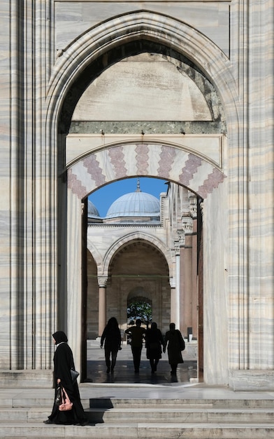 Arco da mesquita, povo árabe e uma mulher em burca preta