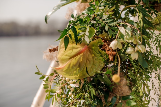 Arco de casamento decorado com flores tropicais verdes e tecido branco