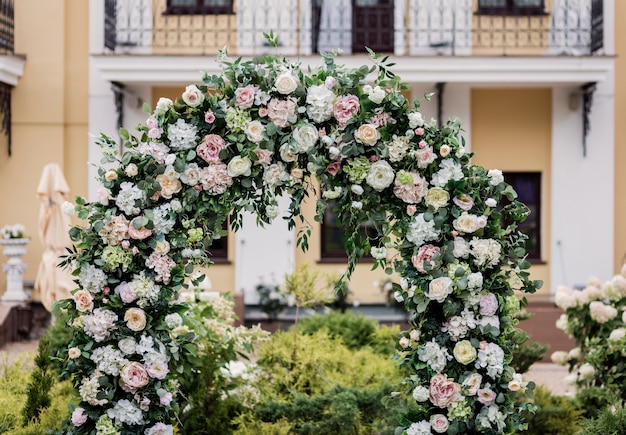 Arco de casamento do círculo decorado com flores brancas e vegetação ao ar livre. Configuração de casamento. Composição floral