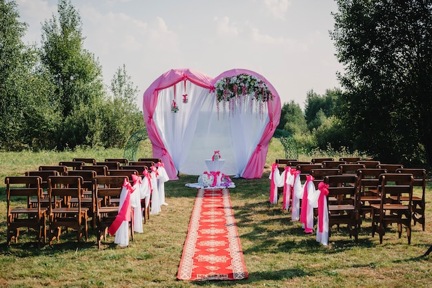 Arco de casamento e cadeiras para cerimônia decorada com flores brancas e rosa