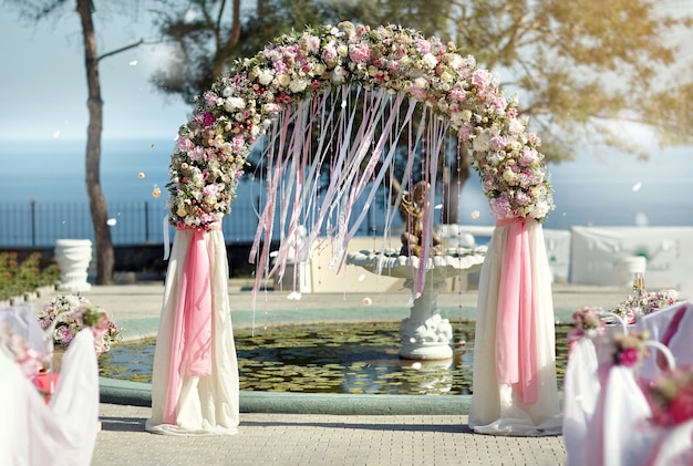 Arco de casamento em fitas e flores contra o mar