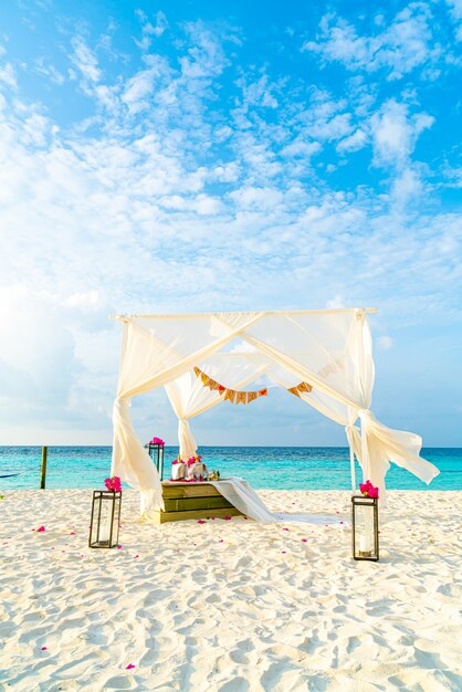 Arco de casamento na praia com mar e resort tropical das maldivas