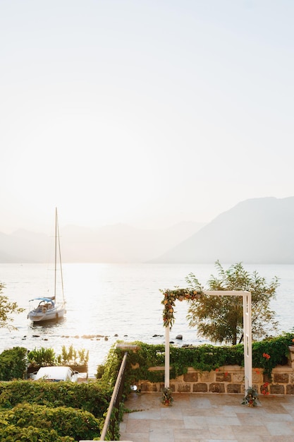 Arco de casamento no deck de observação com vista para o mar com iate flutuante