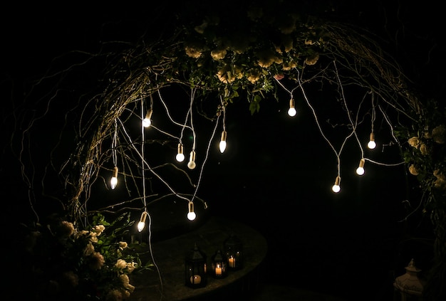 Arco de flores brancas na cerimônia de casamento Decoração ao ar livre Estilo rústico romântico Luzes de lâmpadas à noite