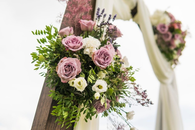 Arco de madeira floral com pano branco e flores brancas rosa violeta frescas com folhas verdes