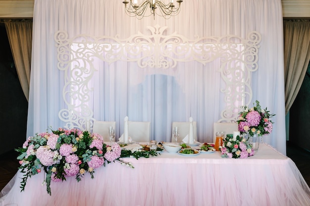 Arco de mesa festivo decorado com composição de flores rosa roxas violetas e velas verdes no salão de banquetes Recém-casados de mesa na área de banquete na festa de casamento