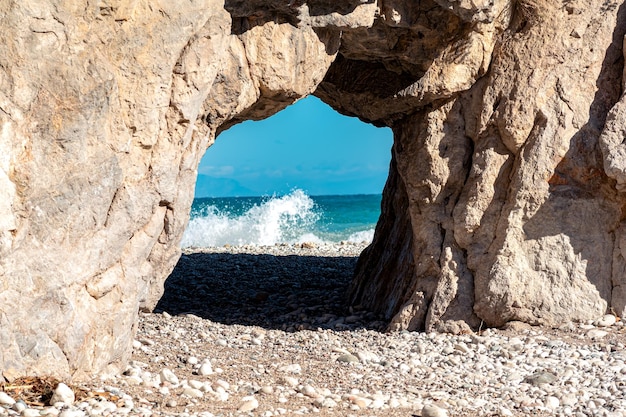 Arco de pedra natural à beira-mar, atrás do qual as ondas do mar podem ser vistas