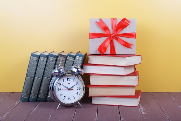 Arco de presente de despertador de ciência e educação e grupo de livros coloridos na mesa de madeira