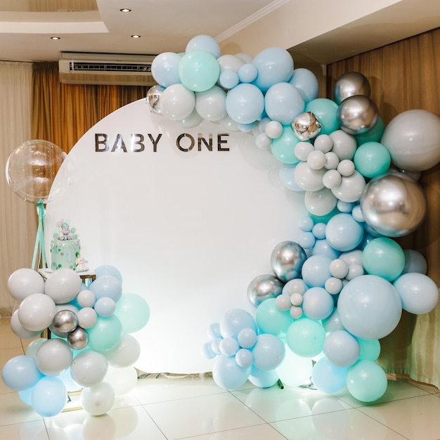 Arco decorado con globos azules, verdes, grises y plateados Baby one party Pastel de moda para 1 año Pastel de cumpleaños en una pared de fotos de fondo Deliciosa recepción en una fiesta de cumpleaños