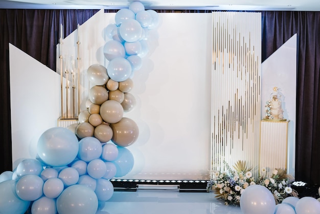 Foto arco decorado con globos marrones dorados azules para cumpleaños fiesta de baby shower decoración de flores de otoño de moda concepto de bautismo de celebración pastel en una pared de fotos de fondo lugar para texto copiar espacio