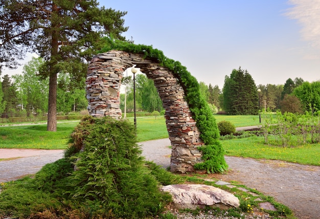 Arco do jardim feito de pedras Jardim decorativo sob o céu azul na primavera Novosibirsk Sibéria Rússia