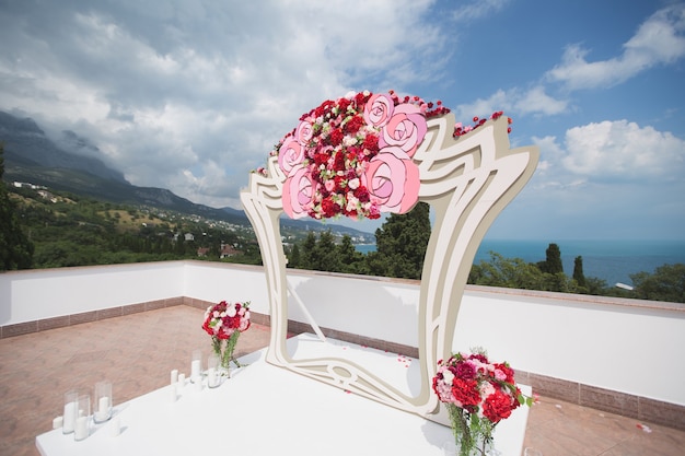 Arco con flores rojas frescas sobre un fondo de cielo azul y mar