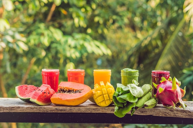 Arco iris de batidos. Sandía, papaya, mango, espinaca y pitahaya. Batidos, jugos, bebidas, variedad de bebidas con frutas frescas en una mesa de madera