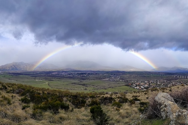 Arco-íris completo espetacular nas montanhas de Madrid, céu com nuvens escuras de chuva. Espanha.