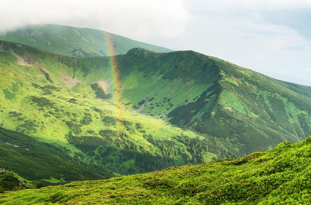 Arco iris bajo la cresta de la montaña Paisaje panorámico en verano