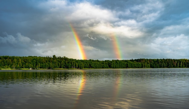 Arco iris doble a través de nubes de lluvia sobre el lago
