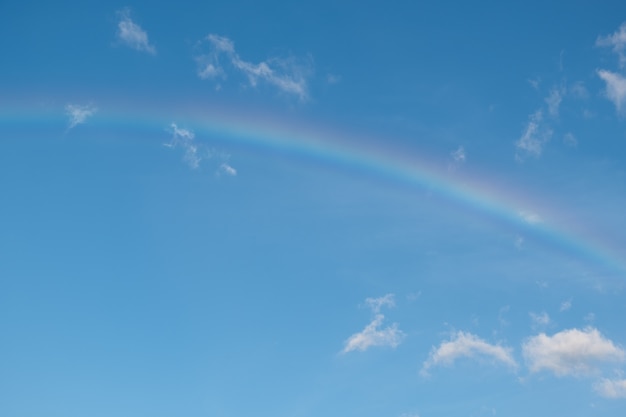 Arco-íris e nuvens brancas no céu azul