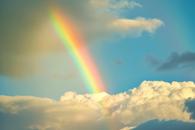 Un arco iris impresionante se extiende a través de un cielo azul con nubes blancas esponjosas un arco ires que se extiende por el cielo después de una tormenta de verano