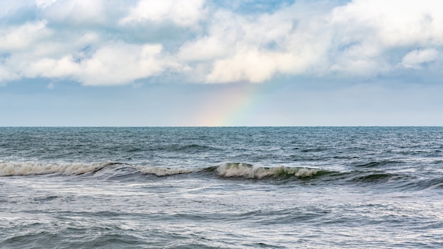 Arco iris sobre el mar tormentoso después de la lluvia