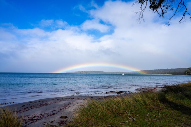 arco-íris sobre o oceano e acima de uma ilha na Austrália