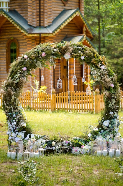 Arco para a cerimônia de casamento. Decorado com flores de tecido e vegetação. Está localizado em uma floresta de pinheiros.