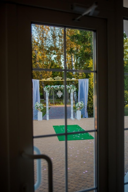 Arco para a cerimônia de casamento O arco é decorado com um pano, um lustre de cristal e flores Vista do arco de casamento da janela Decorações de casamento